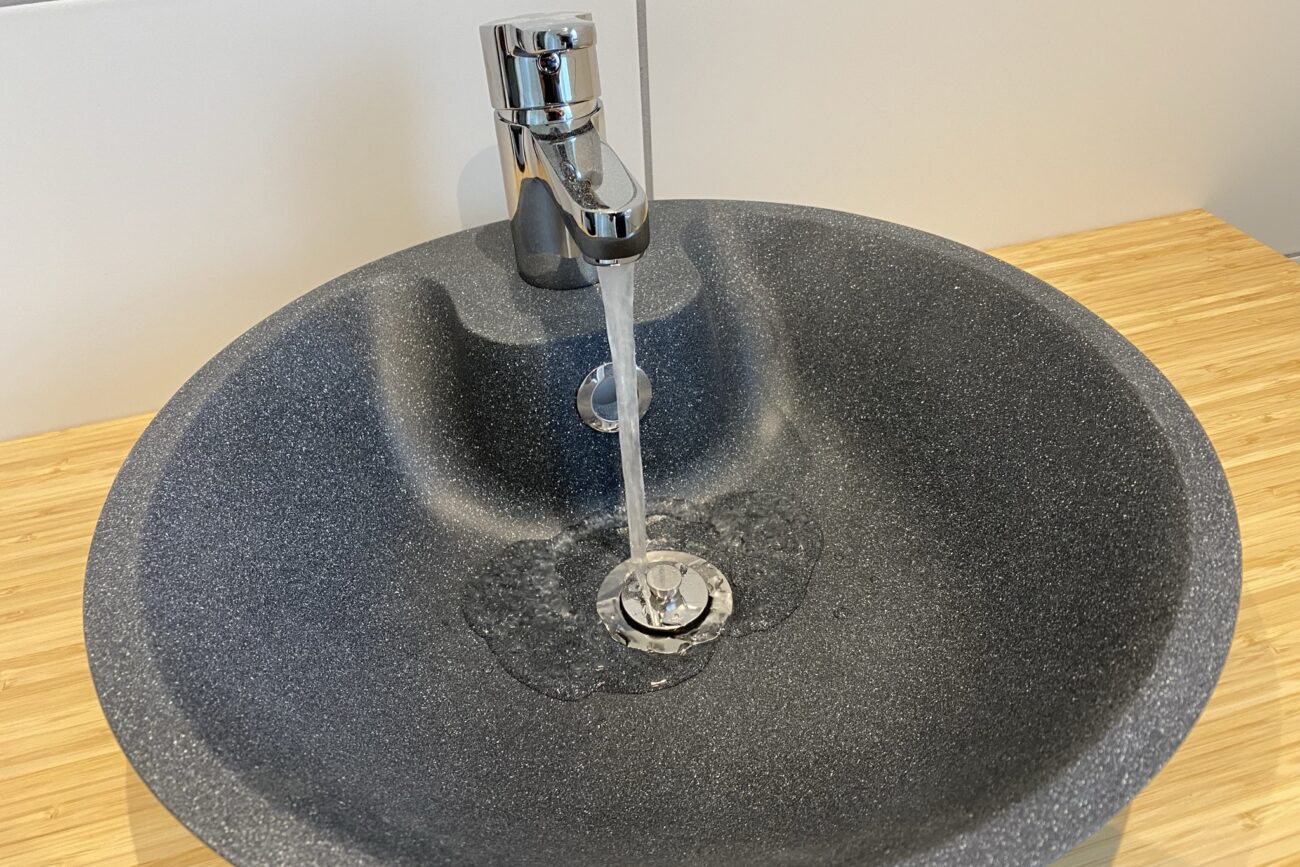 Graues Waschbecken mit laufendem Wasserhahn