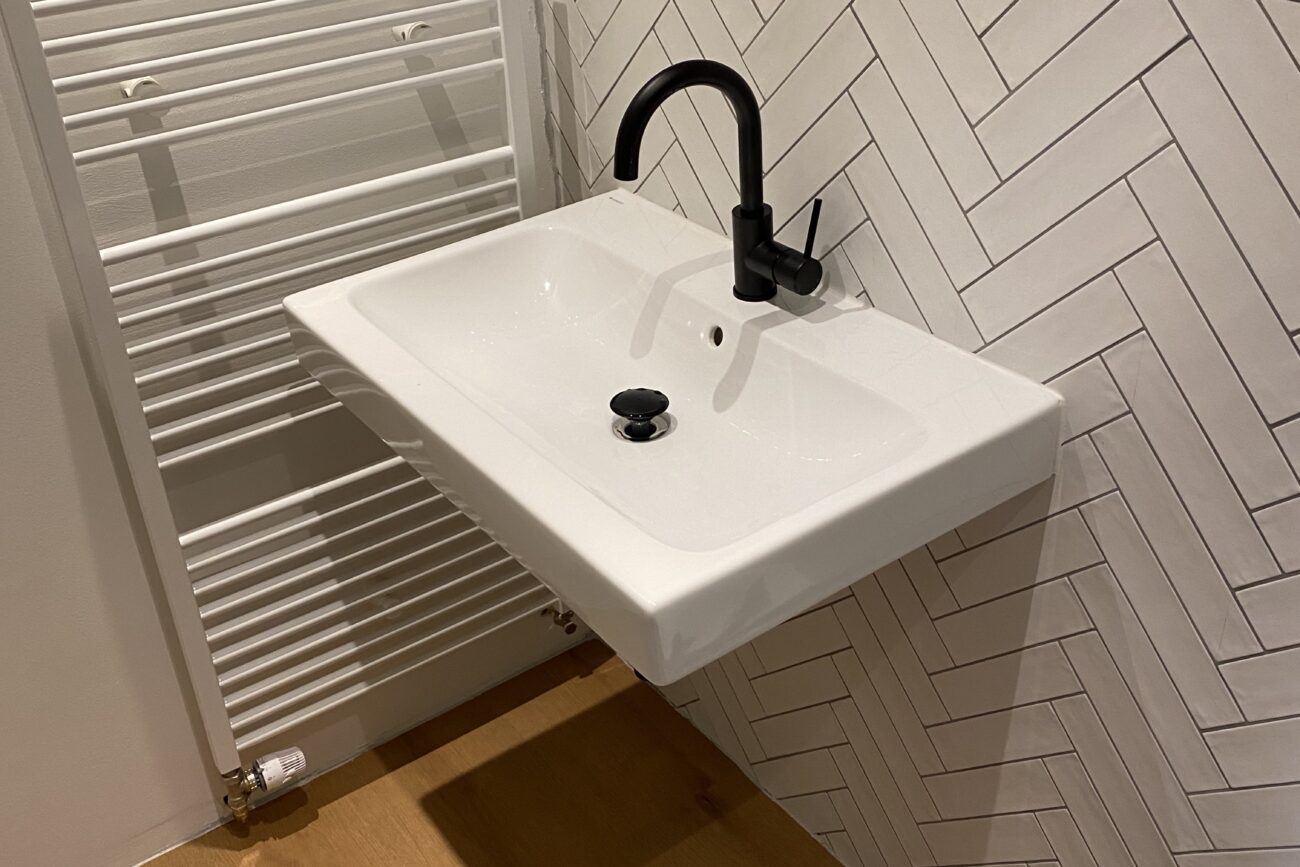 Laminatboden mit weißem Waschbecken und moderner Heizung