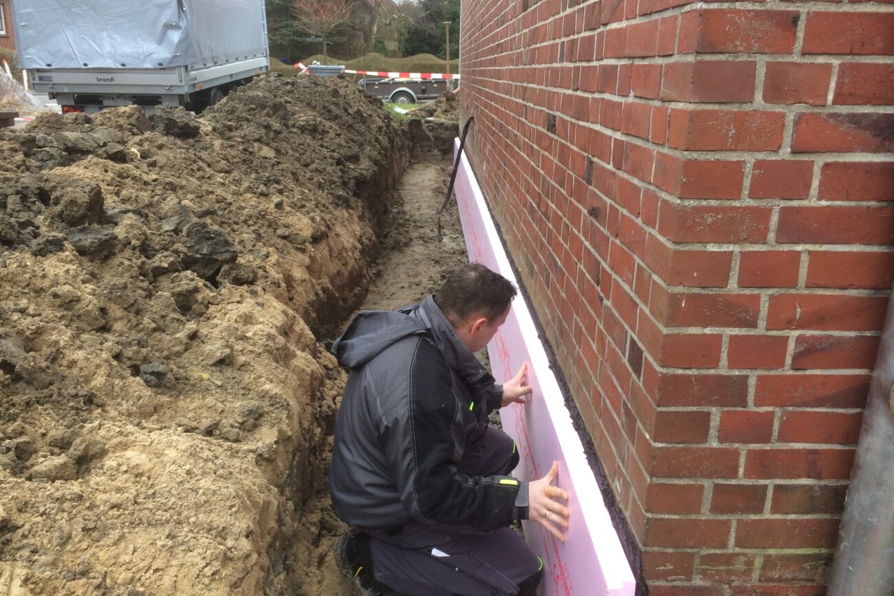 Ein Handwerker behebt einen Wasserschaden an einer Hausaußenwand