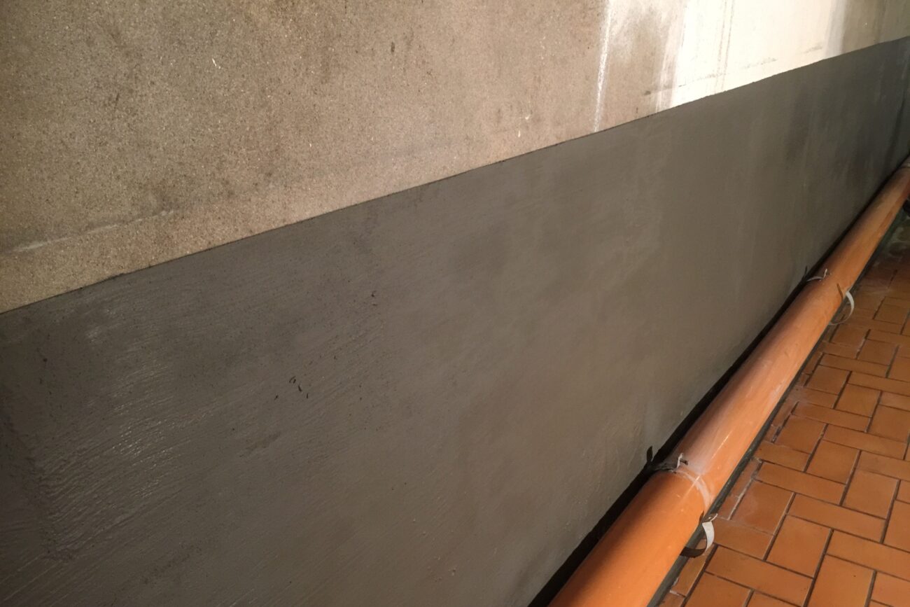 Rohr und verputzte Wand nach einem Wasserschaden in einem Keller