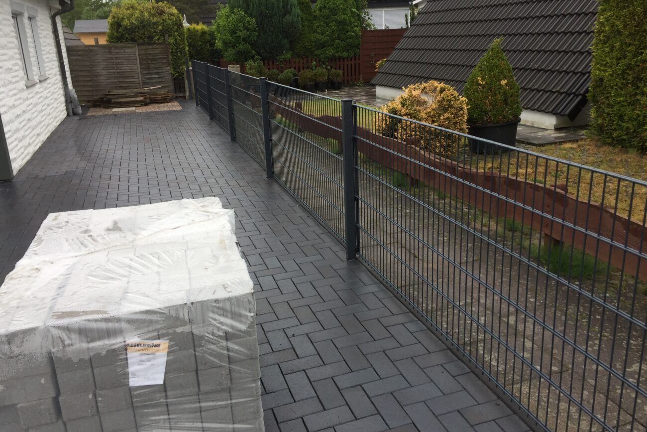 Dunkel gepflasterte Terrasse mit Gartenzaun